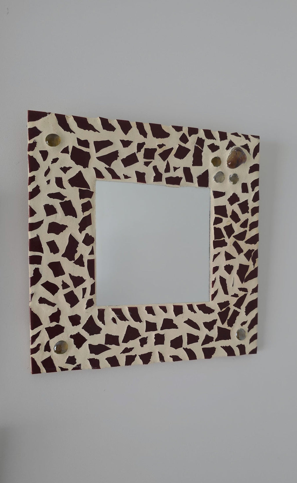 Square mirror with a decorative brown and beige pattern on a gray background