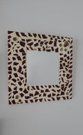 Square mirror with a decorative brown and beige pattern on a gray background