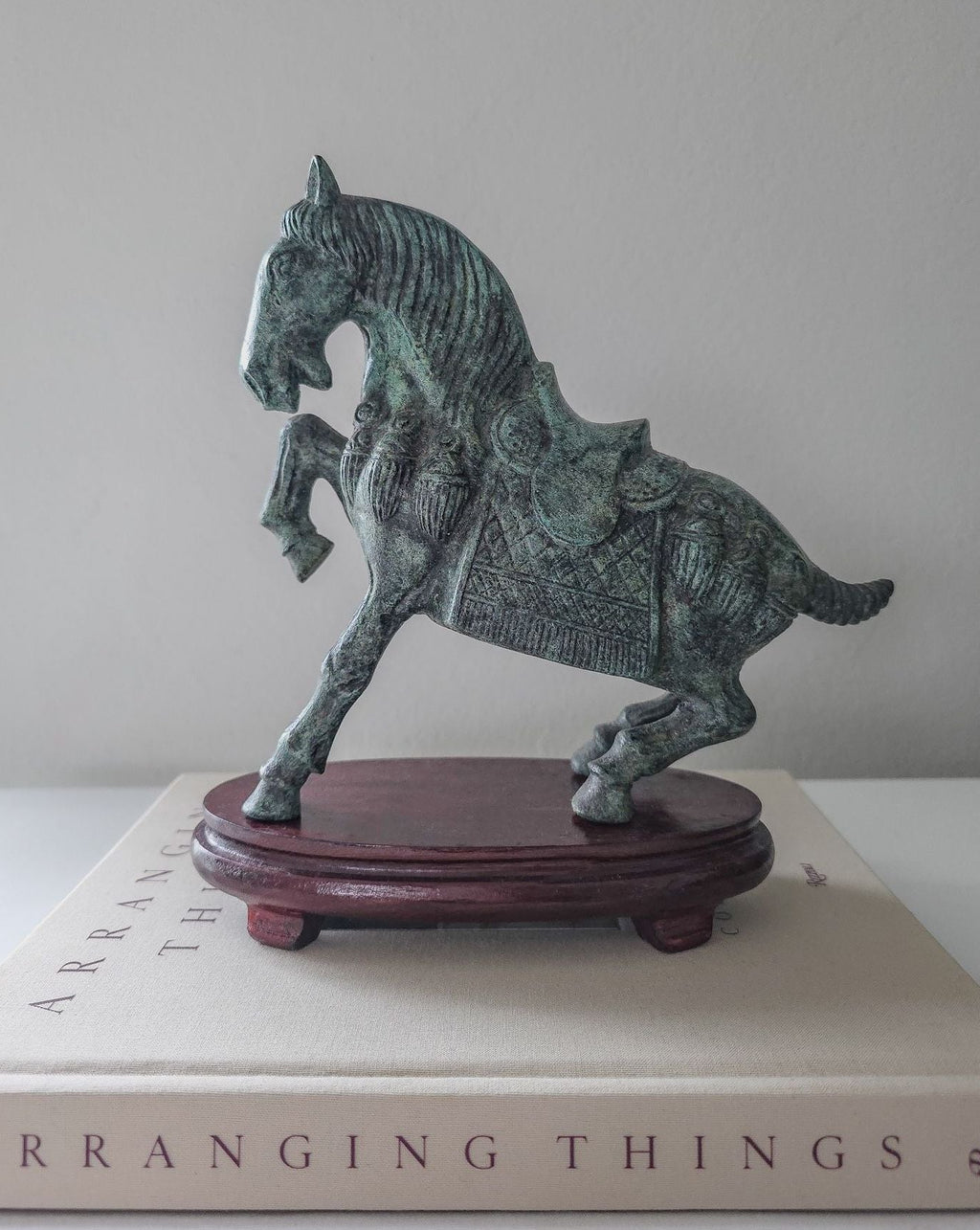Bronze horse sculpture on a wooden base with a book in the background