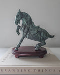 Bronze horse sculpture on a wooden base with a book in the background
